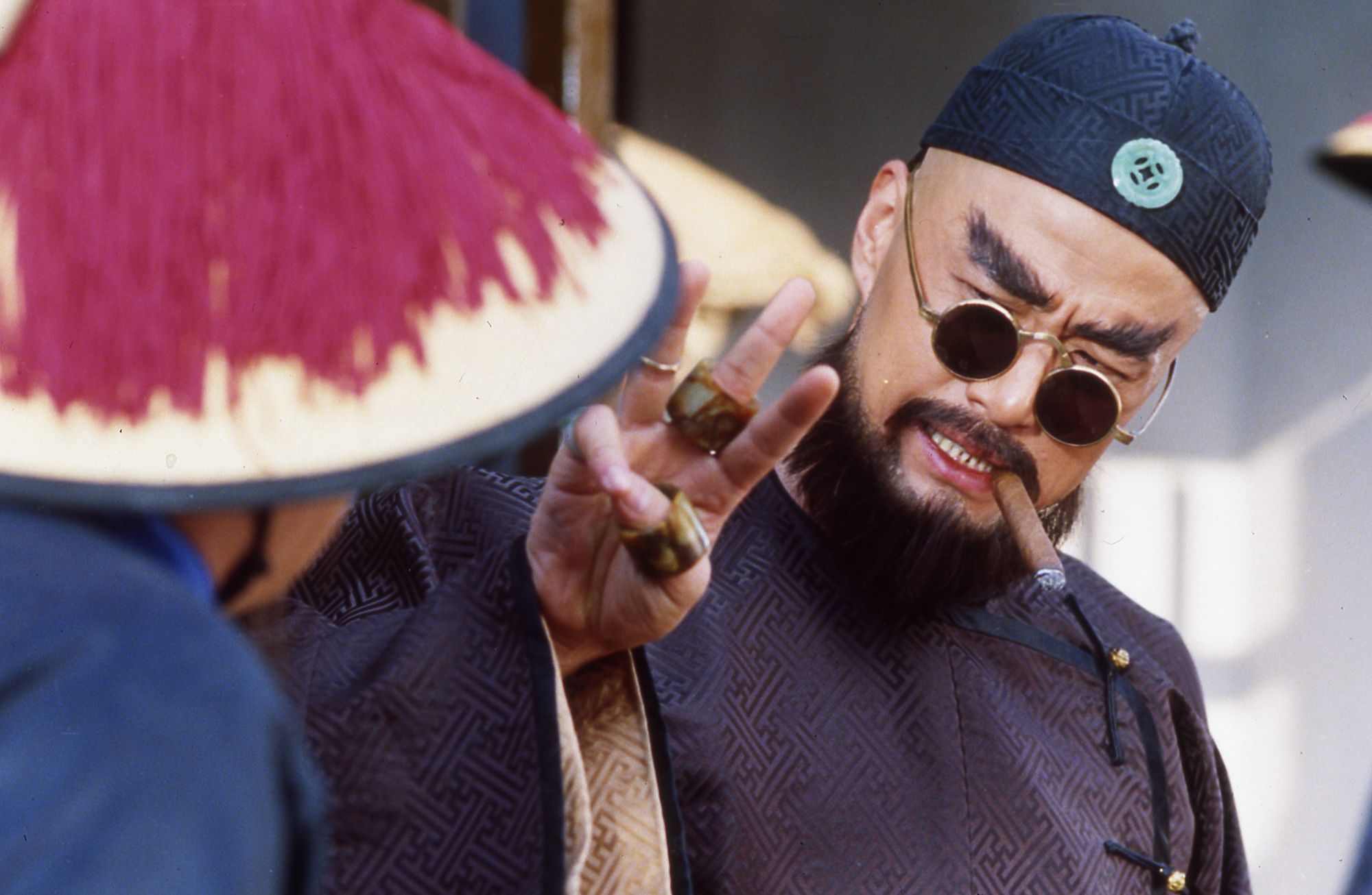 Man holding 3 fingers wearing sunglasses and smoking a cigar