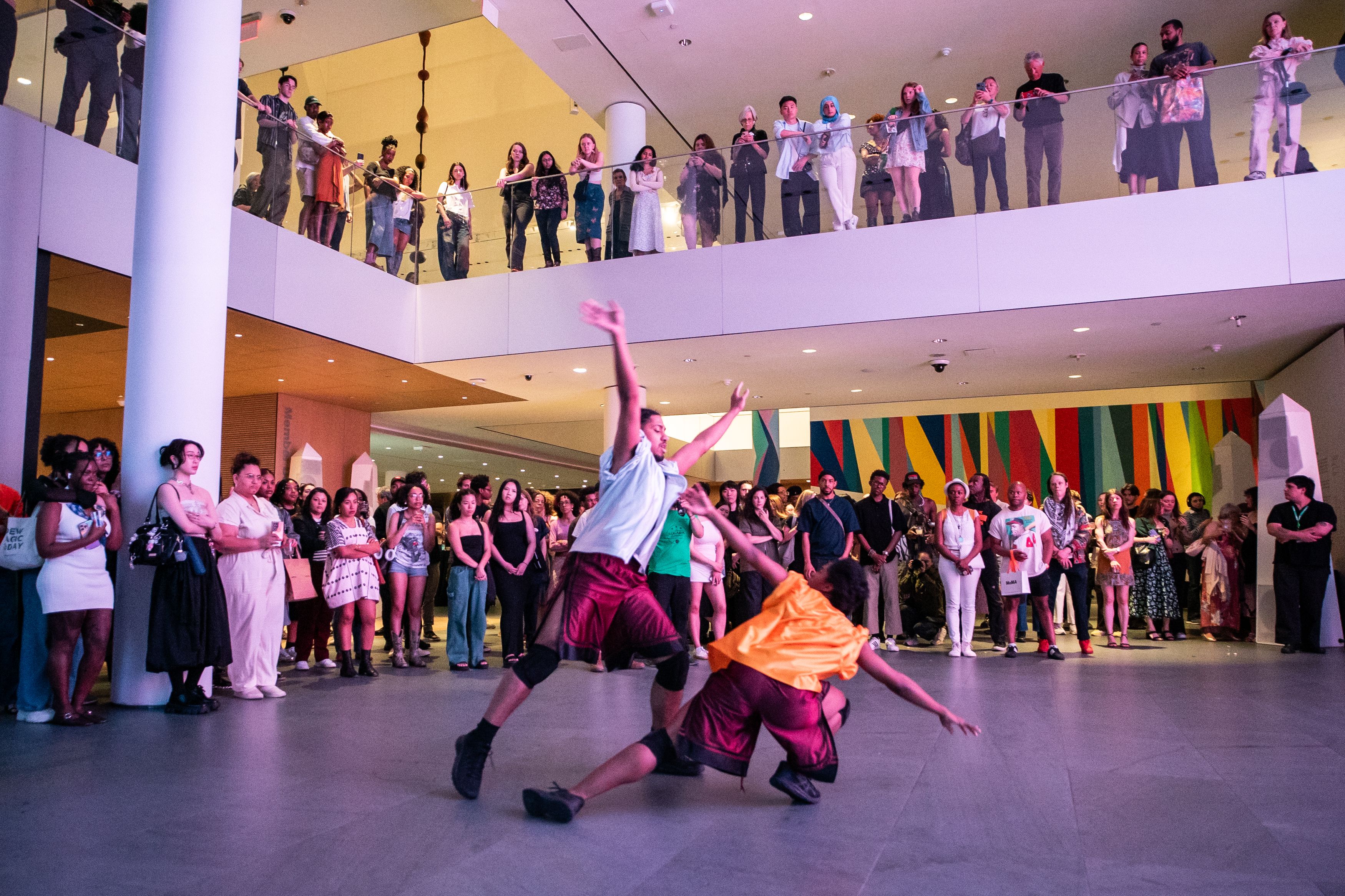 People dancing in an atrium with other people watching 