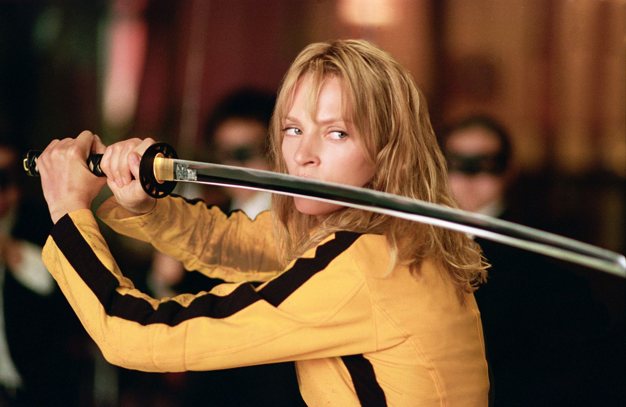 Blonde woman dressing in yellow holds a sword