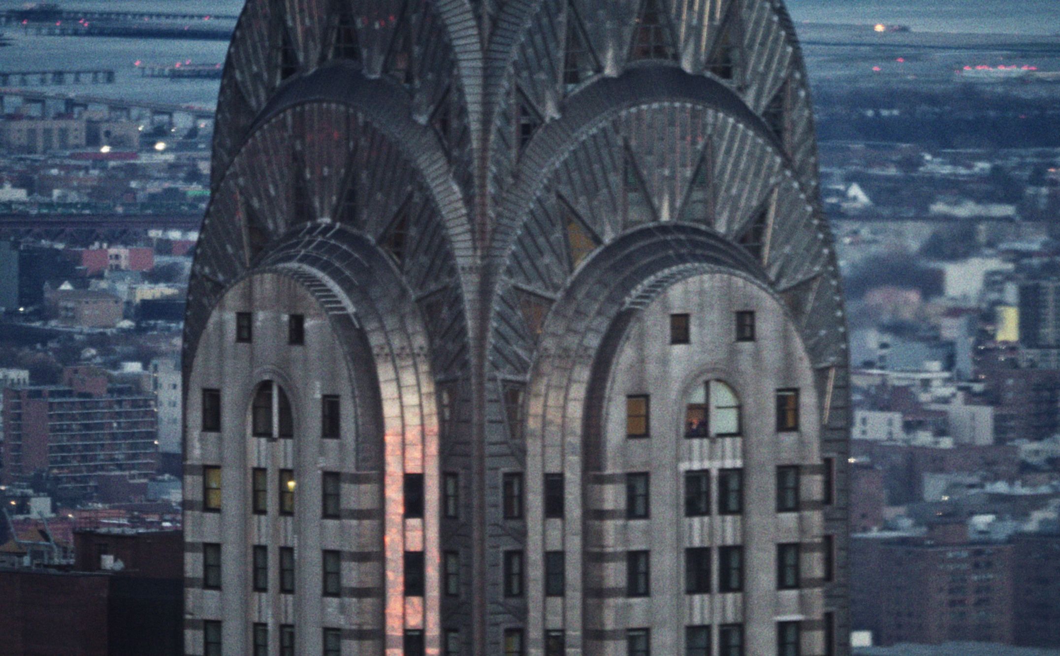 Production shot showing a photo of a brick apartment building rooftop at sunset, with the shadows of three people visible on the brick exterior