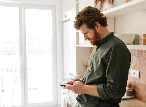 Man wearing green shirt heads down on his phone concentrating.