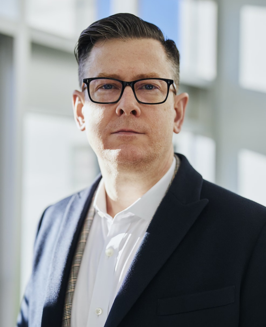 Investor wearing suit standing by tall building.