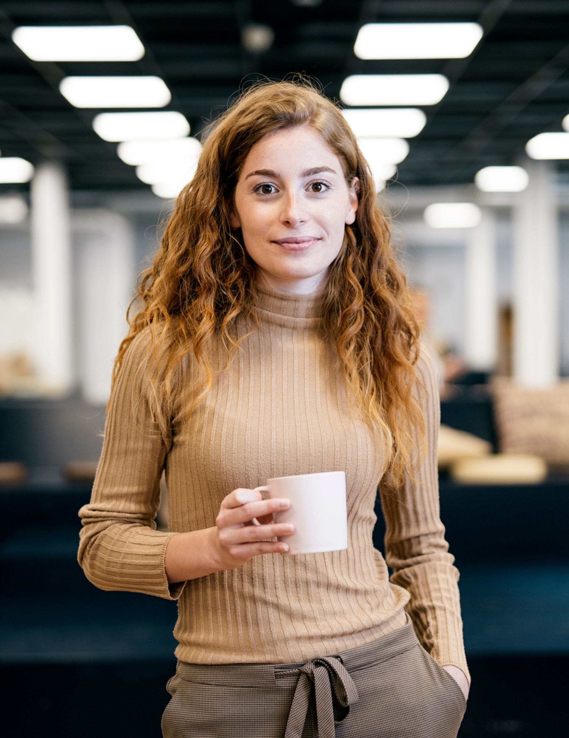 Woman holding cup of coffee in office. 
