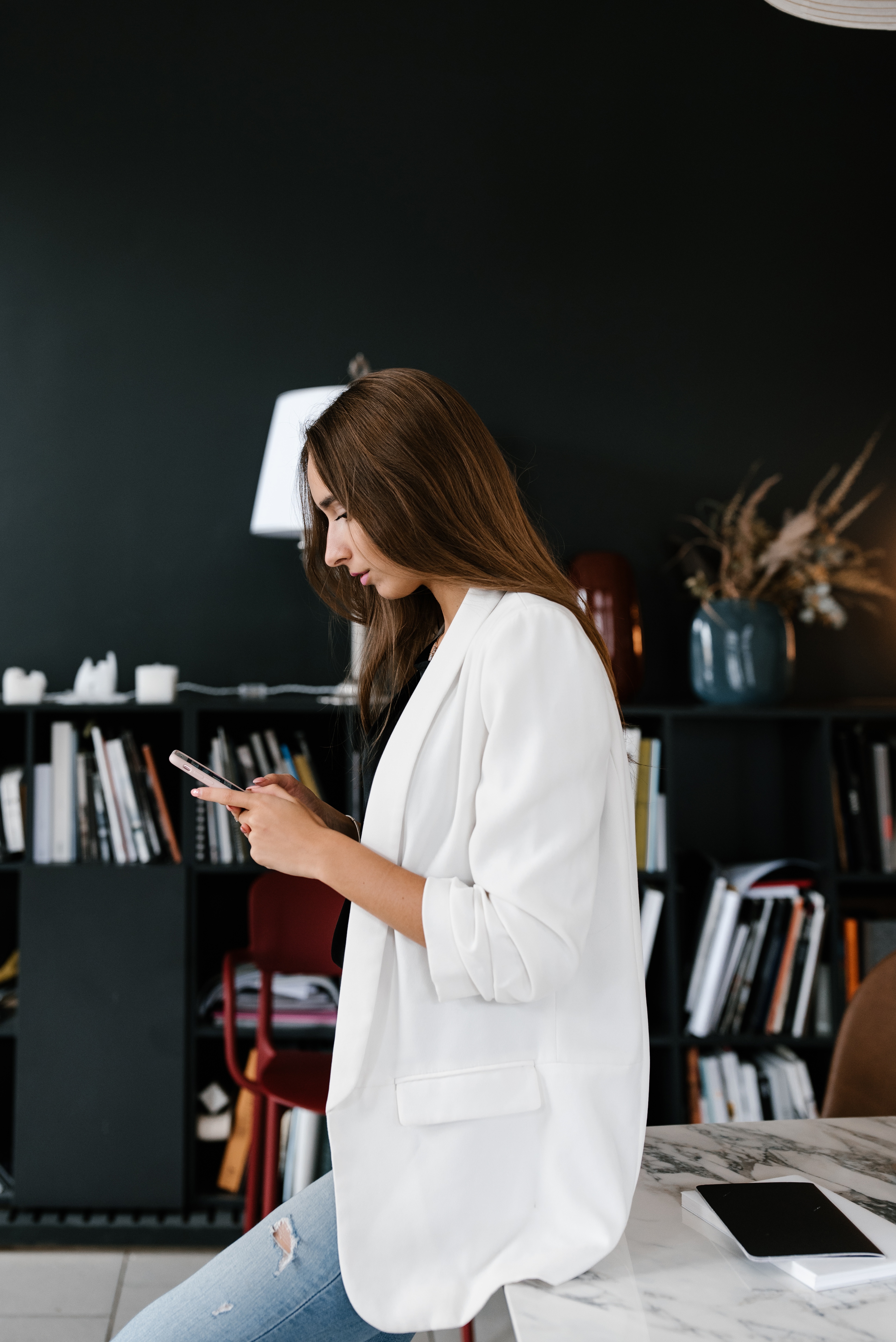 Woman sitting on her desk looking down at phone.