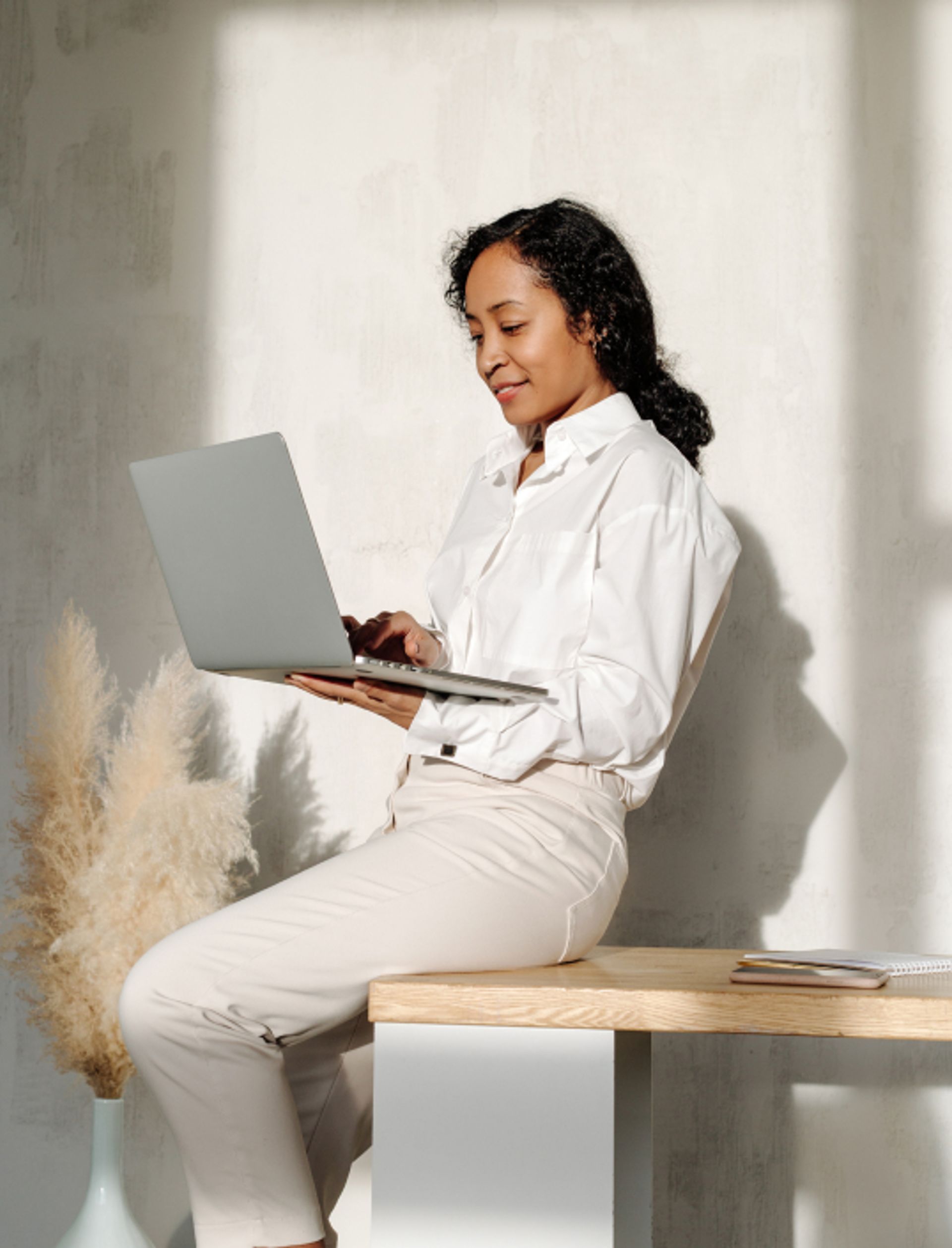 Woman holding laptop and smiling as she works. 