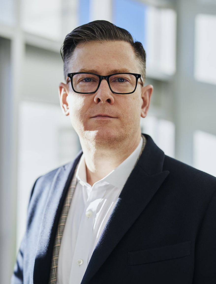 Investor wearing suit standing by tall building. 