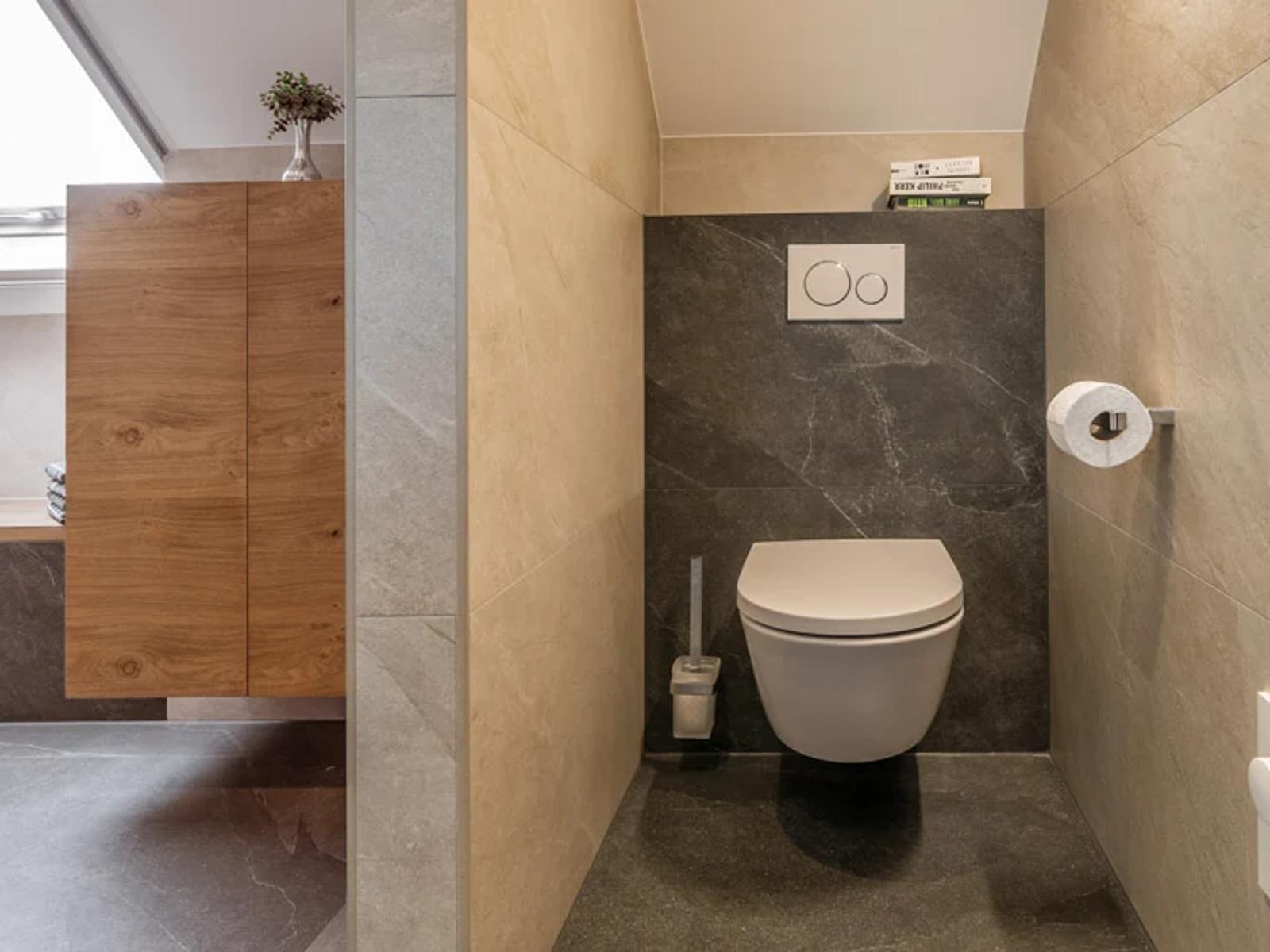 Modernes Badezimmer mit WC und Holzschrank.