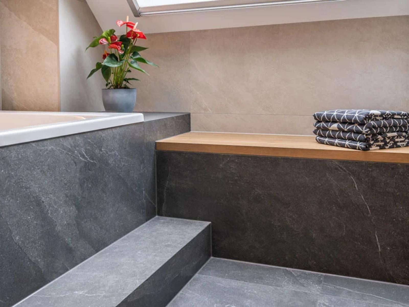 Modernes Badezimmer mit Badewanne, Holzregal und Pflanzen.