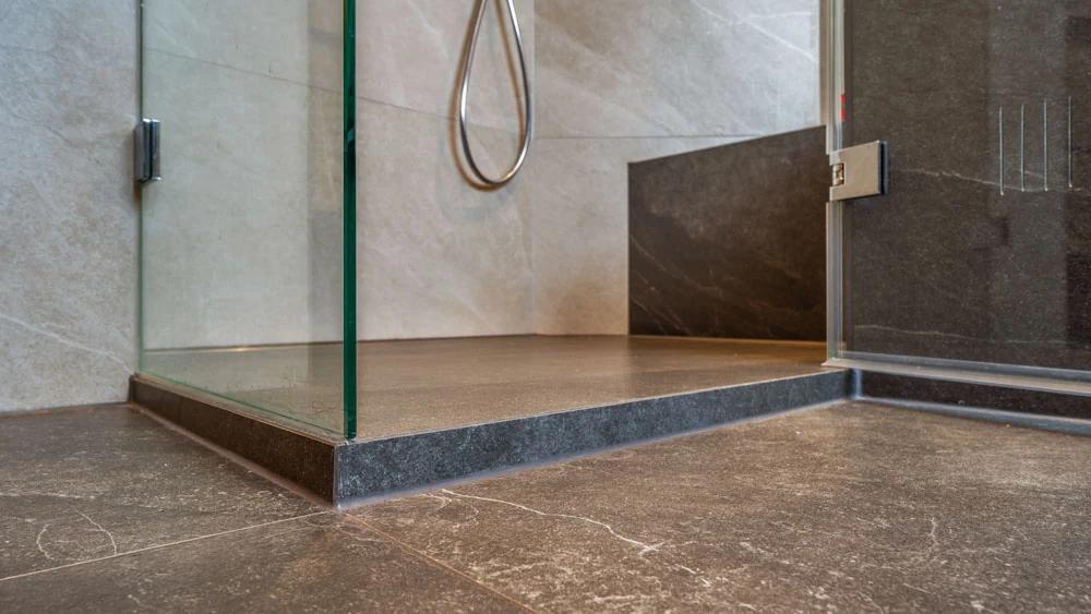 Moderne Dusche mit Glaswand und dunklem Bodenbelag.