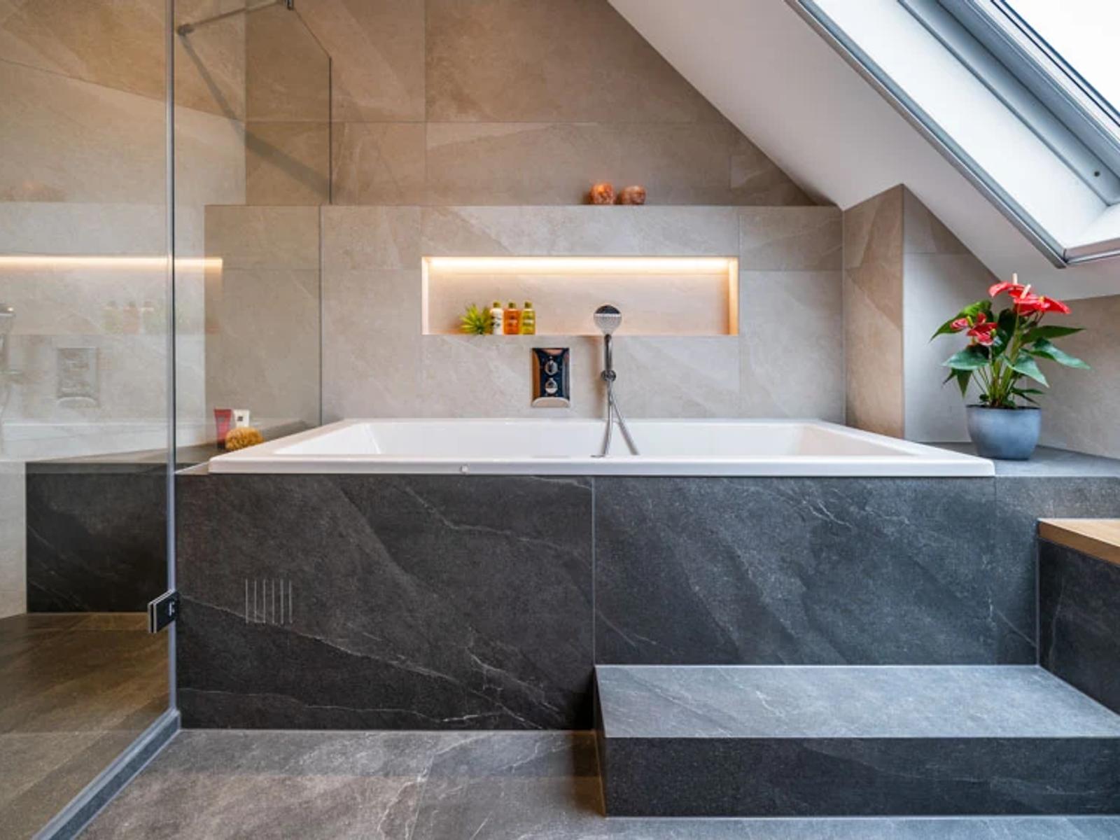 Modernes Badezimmer mit Badewanne, Dusche und Pflanzen.