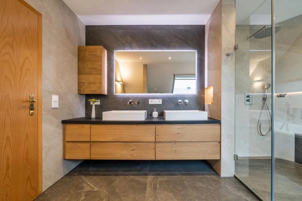 Modernes Badezimmer mit Holzschränken und Doppelwaschbecken.