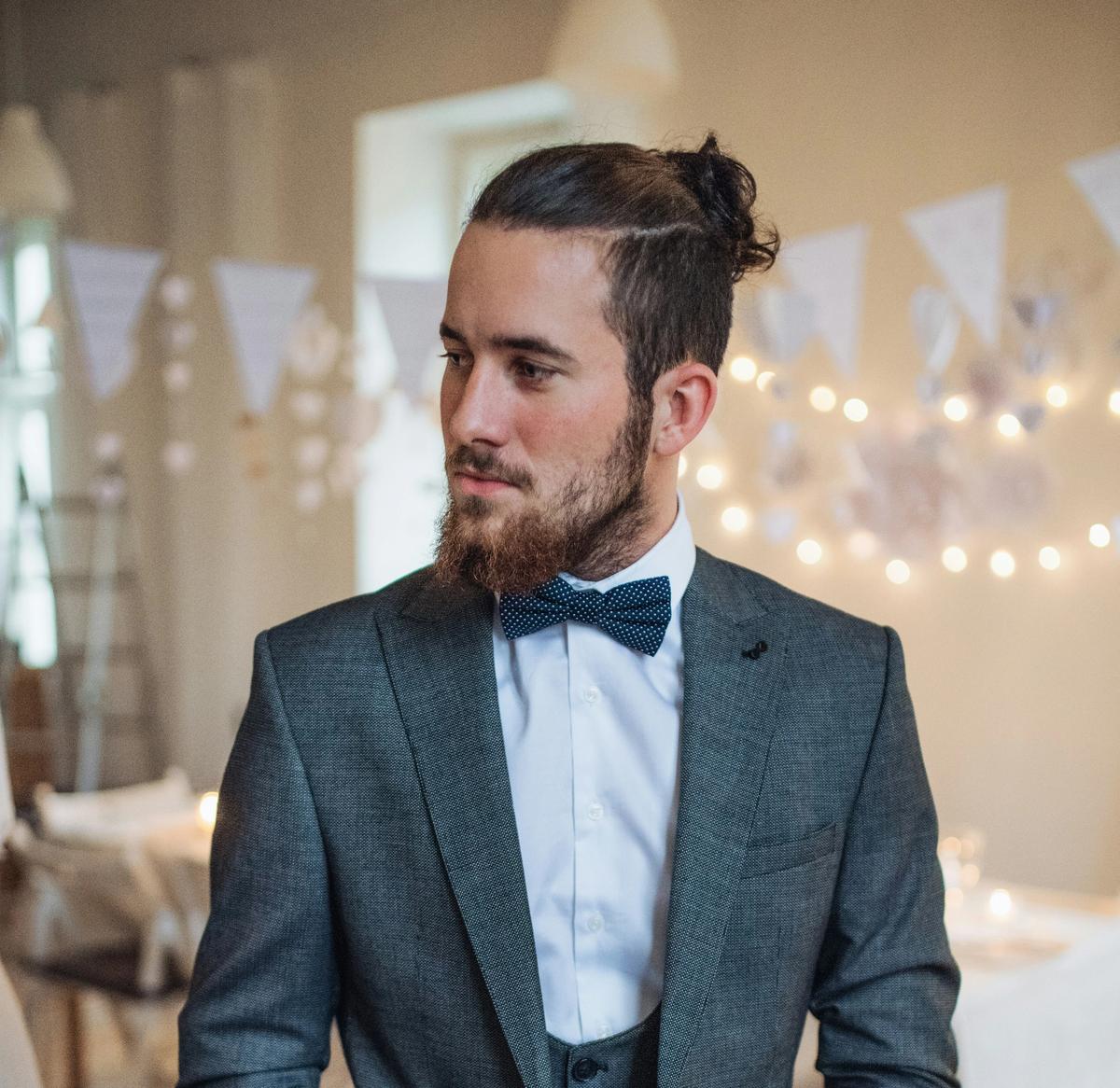 Man in textured tuxedo with party in the background