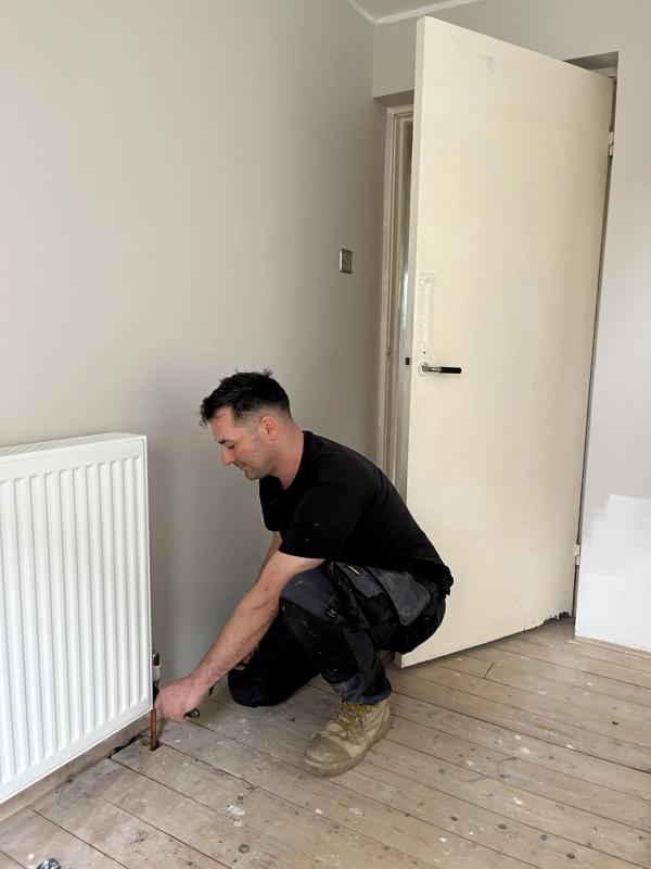 A radiator lifted clear of its brackets so the wall behind it can be decorated