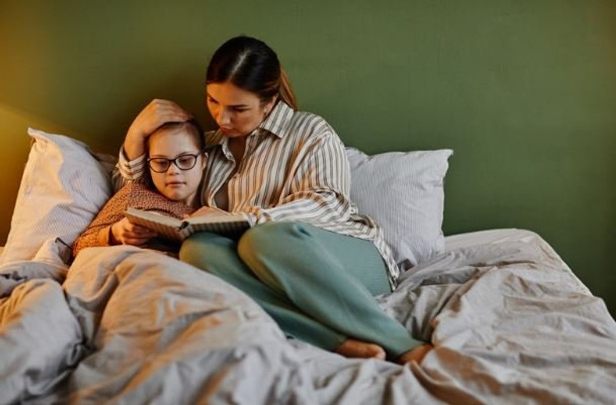 Parent reading a bedtime story to a child in bed as part of a calming sleep routine