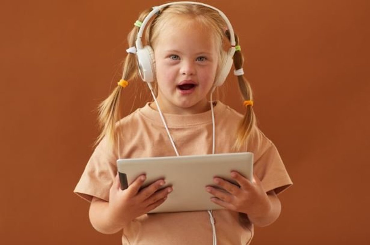 Young girl with Down syndrome wearing headphones and holding a tablet