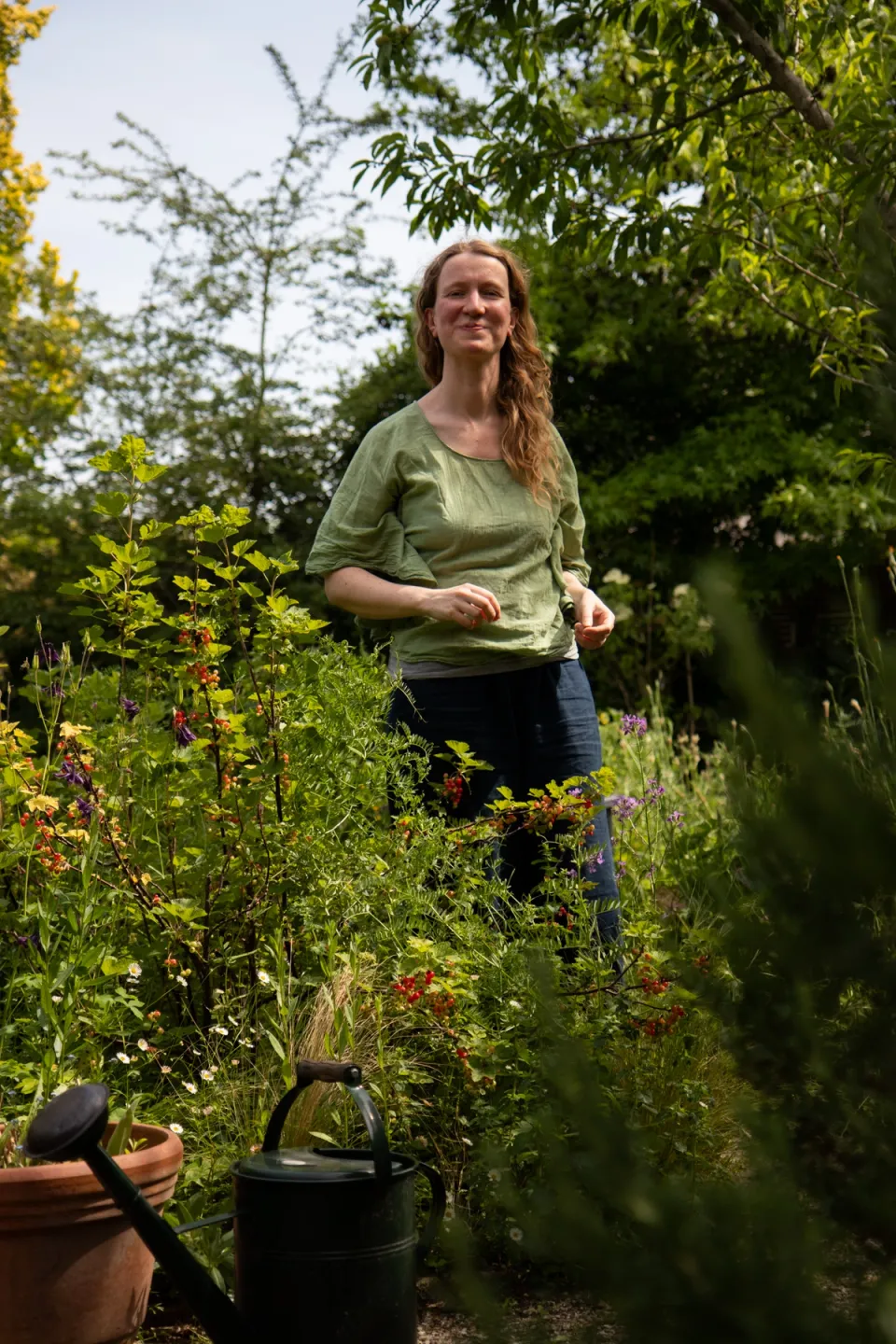 Faelyn, watercolor artist, in her cottage garden next to the red currant bushes