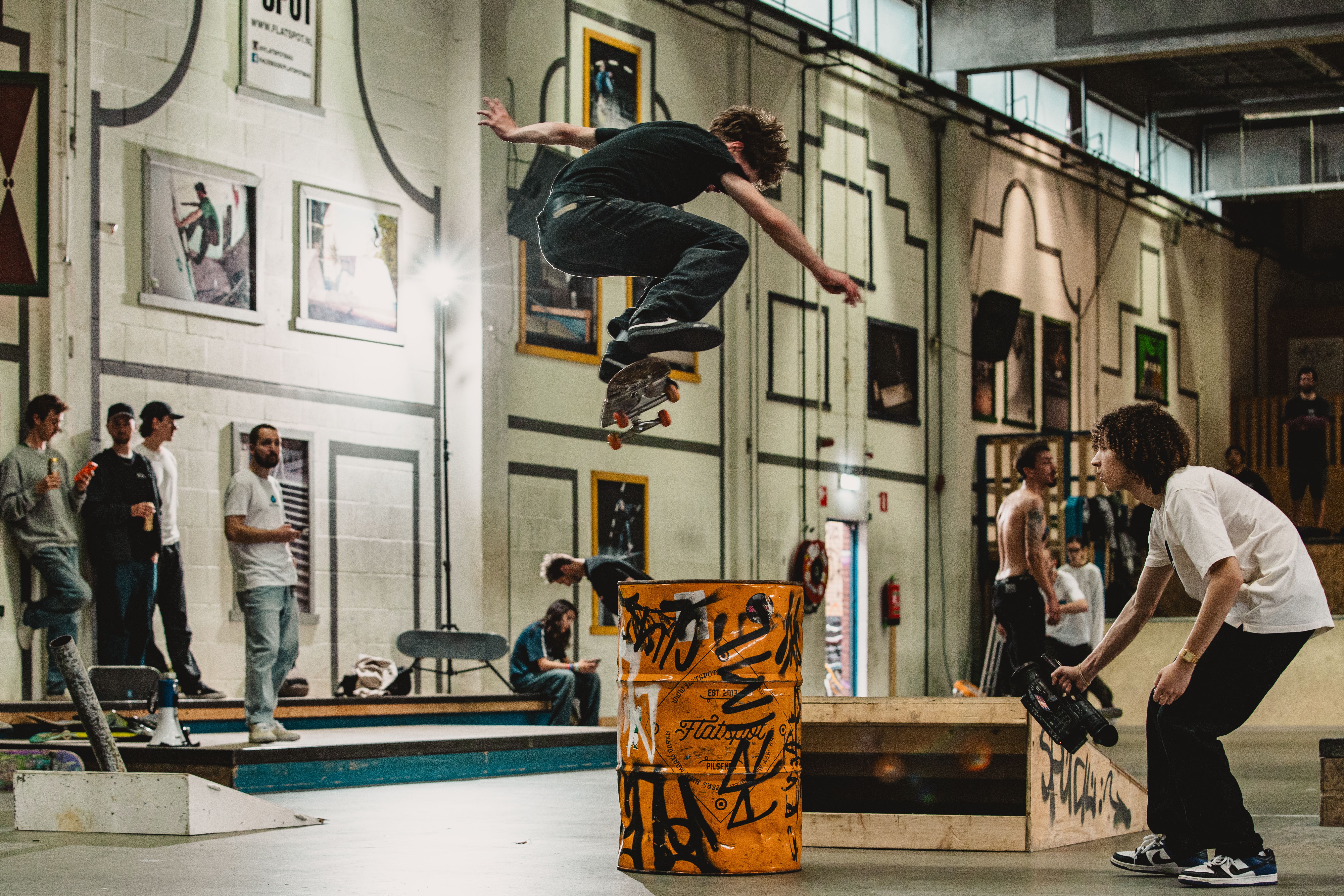 [PLACEHOLDER] Een skater vliegt over een gele ledge terwijl anderen toekijken
