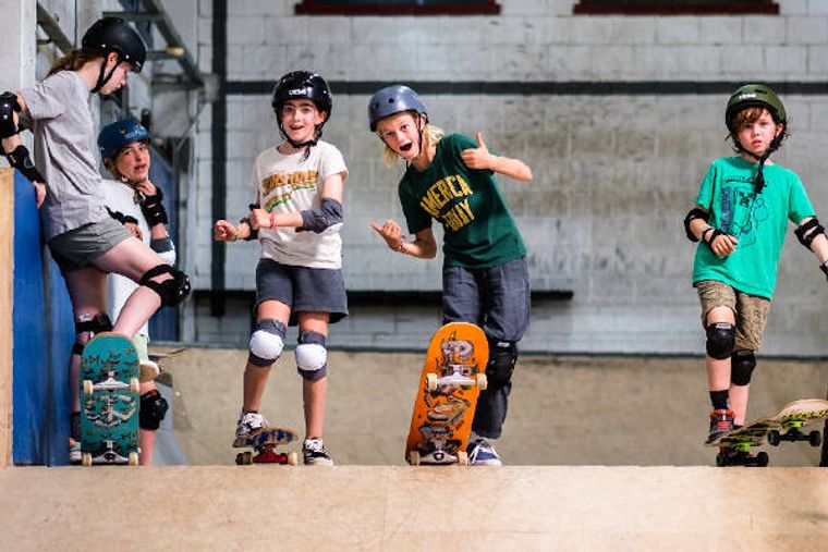 Vier kinderen met hun boards, lachend, met de duimen omhoog.