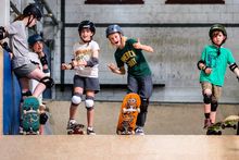 Vier kinderen met hun boards, lachend, met de duimen omhoog.
