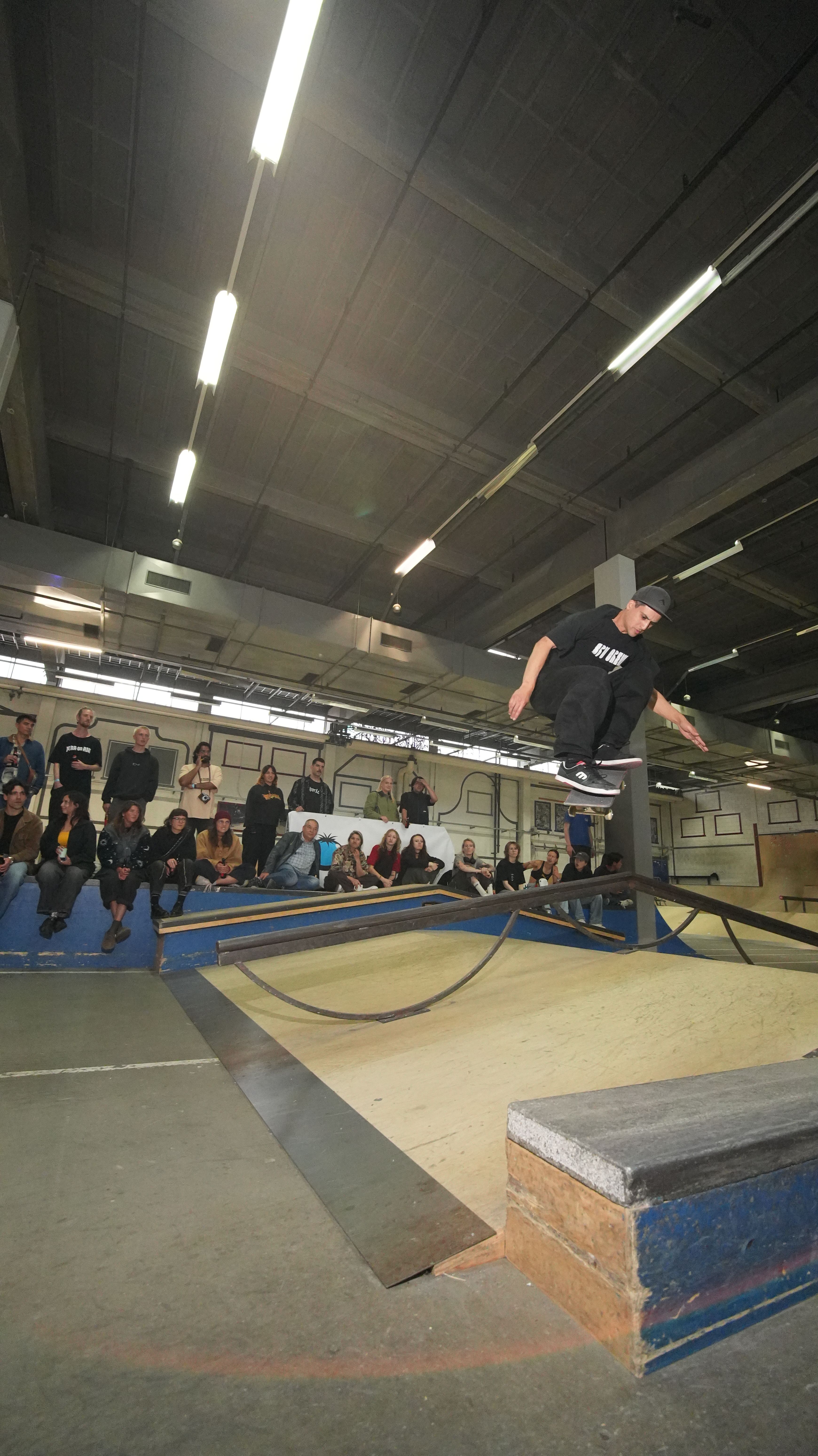 [PLACEHOLDER] Een skater glijdt over een rail voor een volle rand toeschouwers