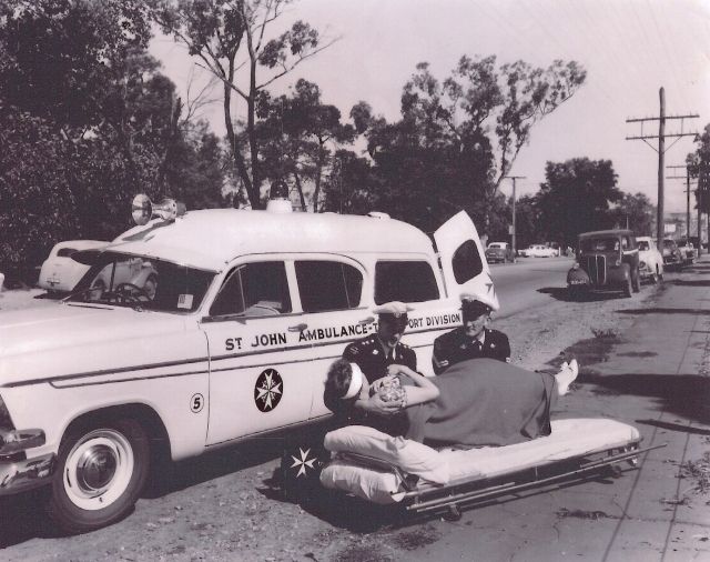 Vintage St John ambulance crew attending to a patient on a stretcher