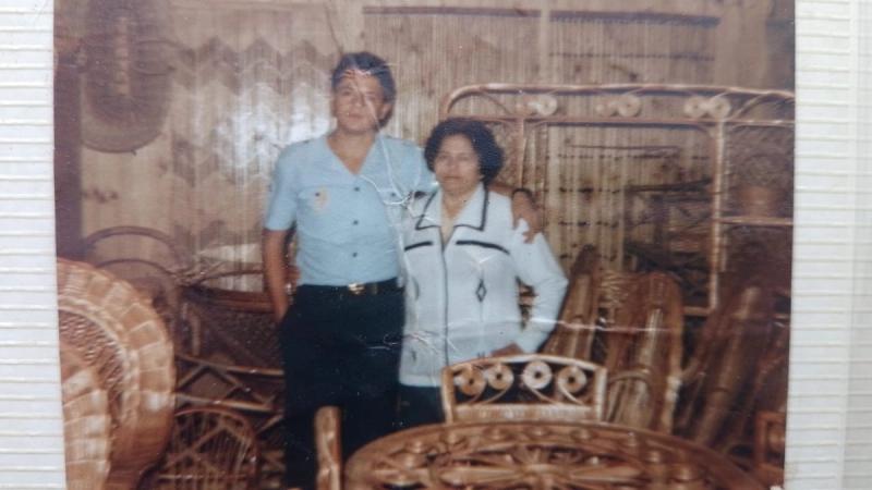 Um homem e uma mulher posam lado a lado dentro de uma loja de móveis em fibras.