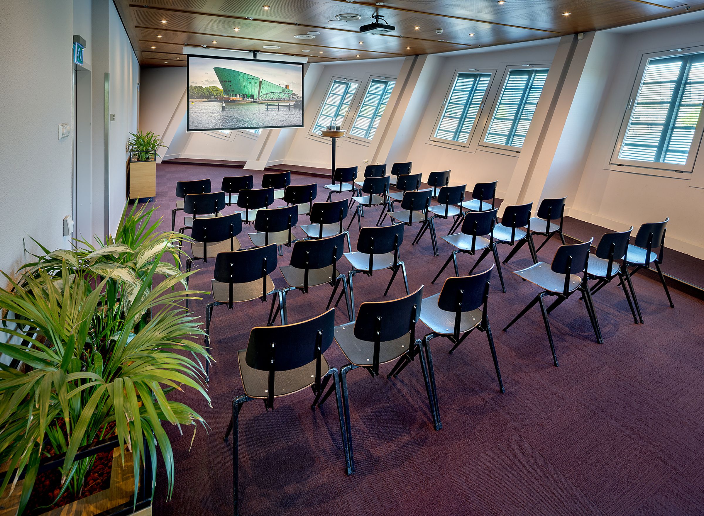 Ovale ruimte met bruine stoelen in theateropstelling.