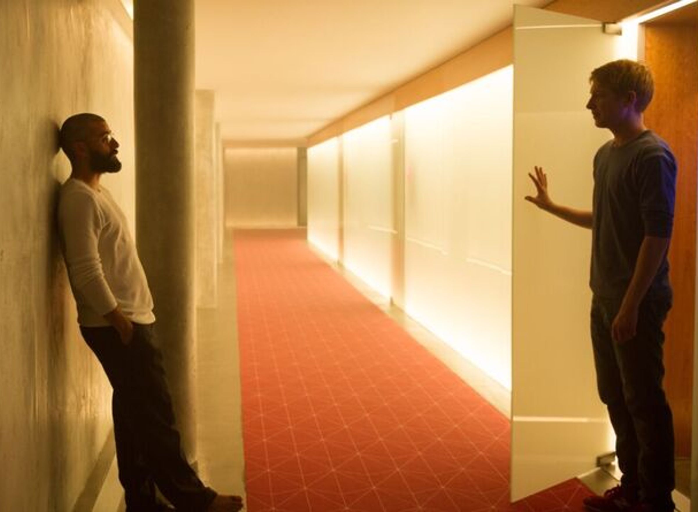 Two men are standing facing each other in a corridor.