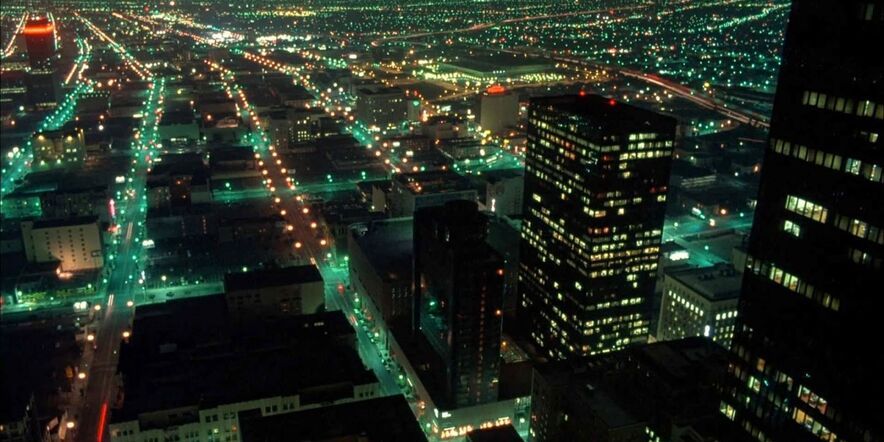 Een nachtelijke verlichte stad met wegen en flatgebouwen van boven gefotografeerd.