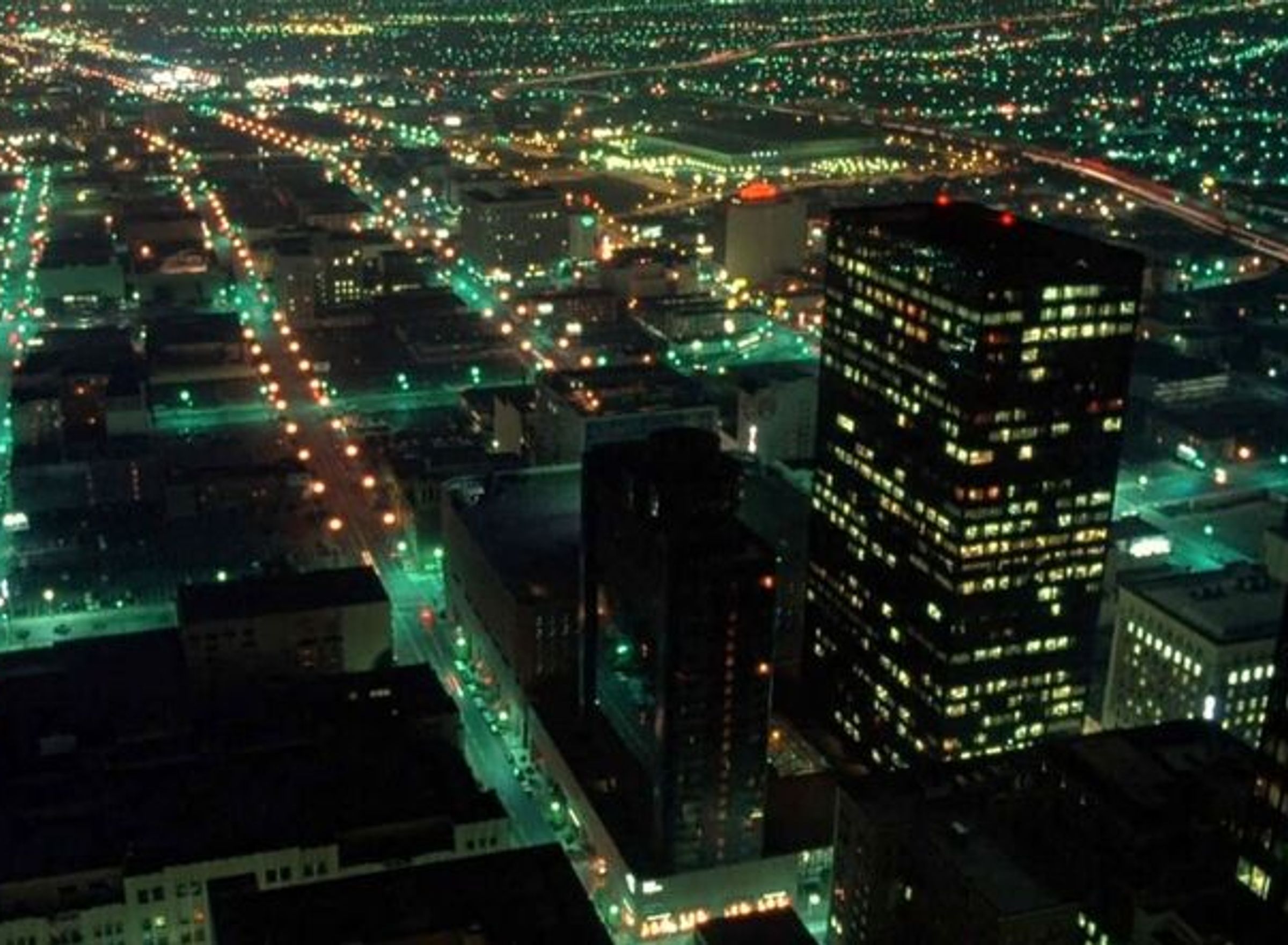Een nachtelijke verlichte stad met wegen en flatgebouwen van boven gefotografeerd.