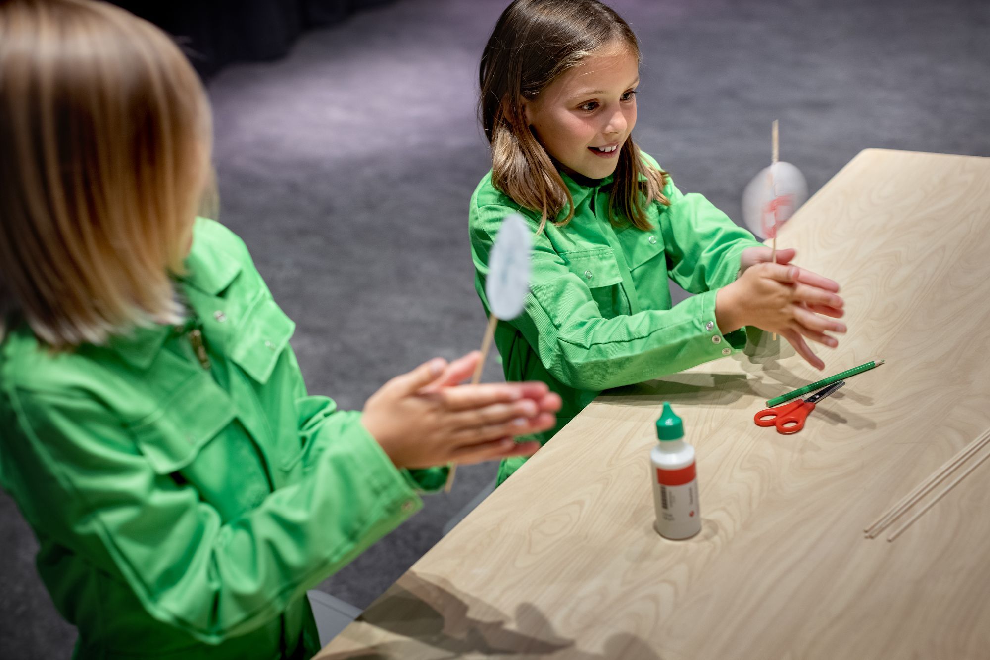 Twee meisjes draaien satéprikkers waaraan rondjes papier geplakt zijn