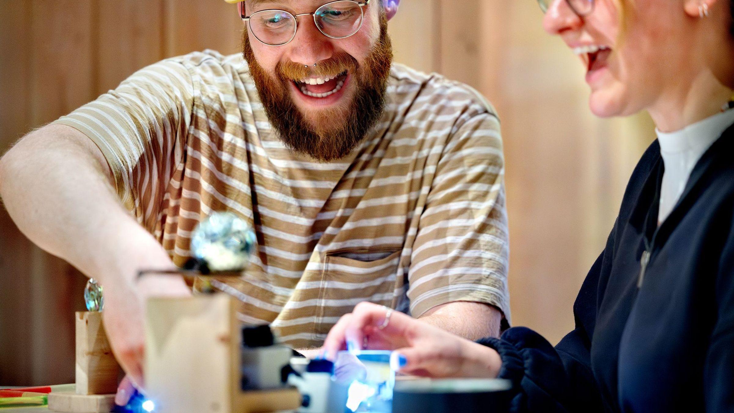 Een man en een vrouw zitten naast elkaar en werken samen aan het maken van een lichtbaan.