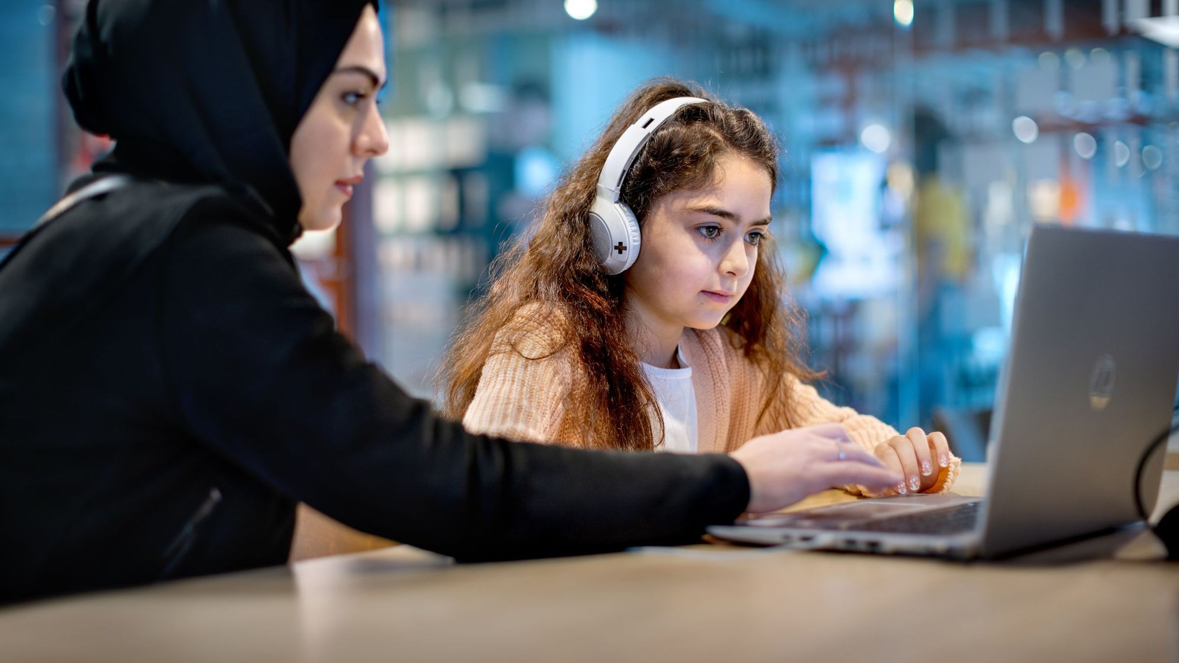 een meisje en een vrouw zitten samen achter een laptop
