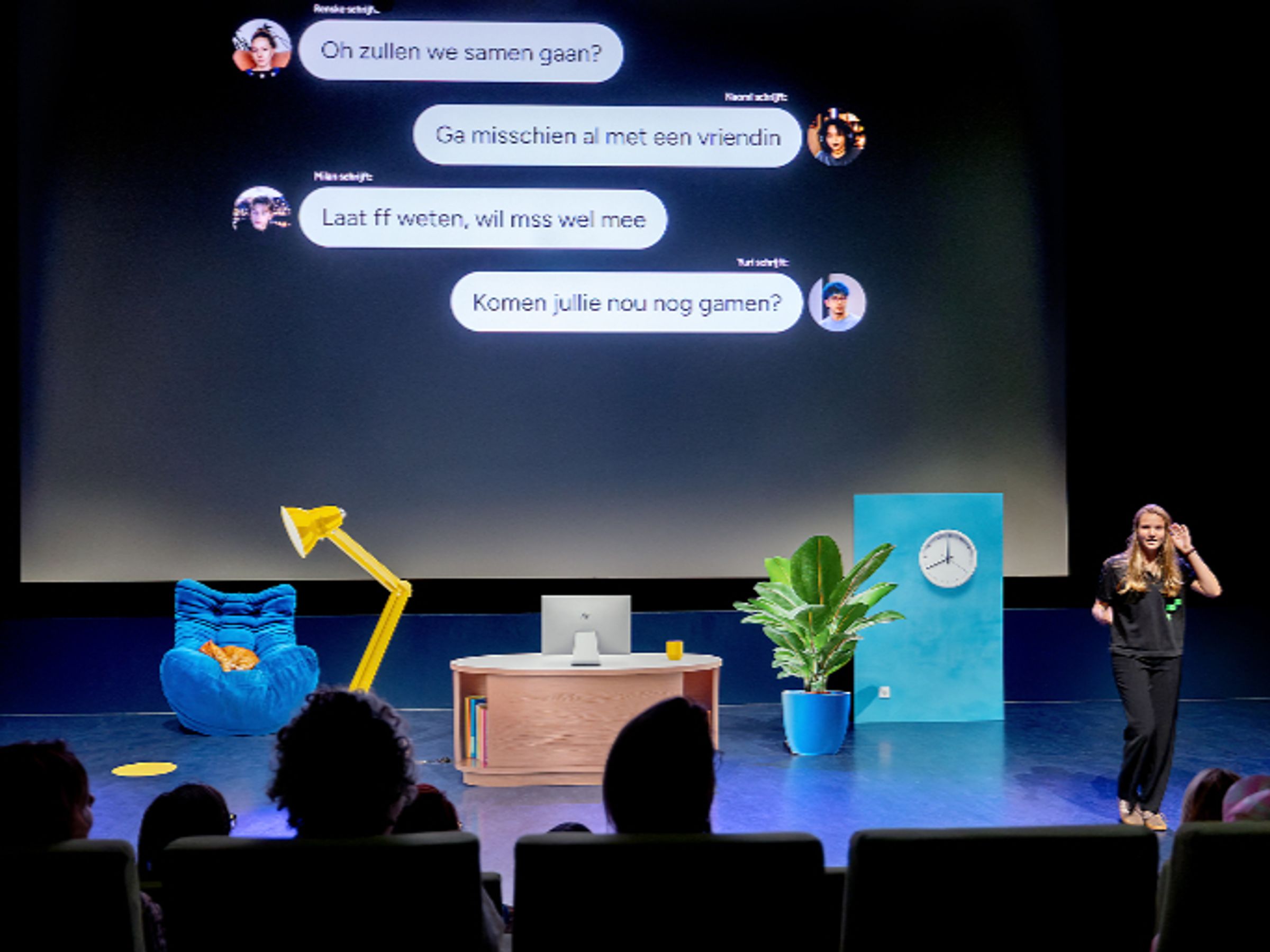 Een vrouw staat voor een decor met daarachter een groot digitaal scherm met tekstballonnen en een de