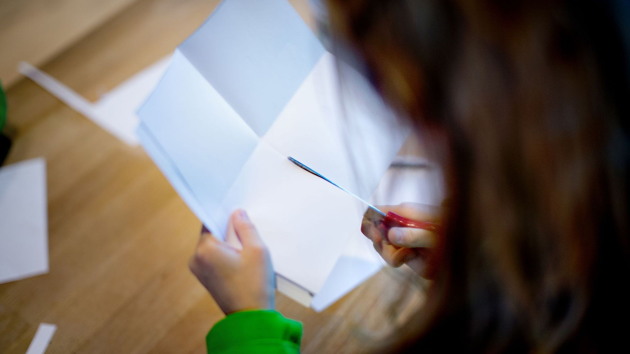 Een kind knipt met een schaar in een papier.