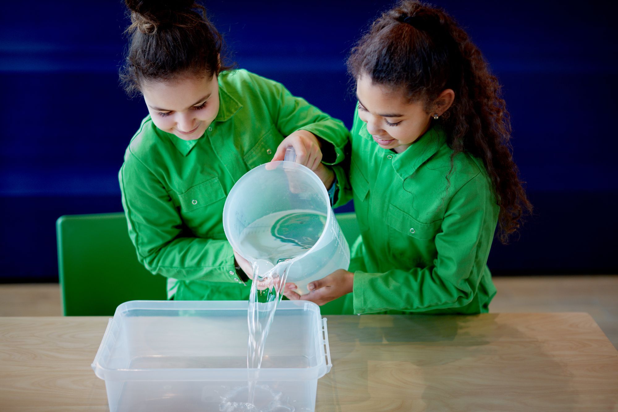 Twee meisjes zijn bezig met het vullen van een bak water
