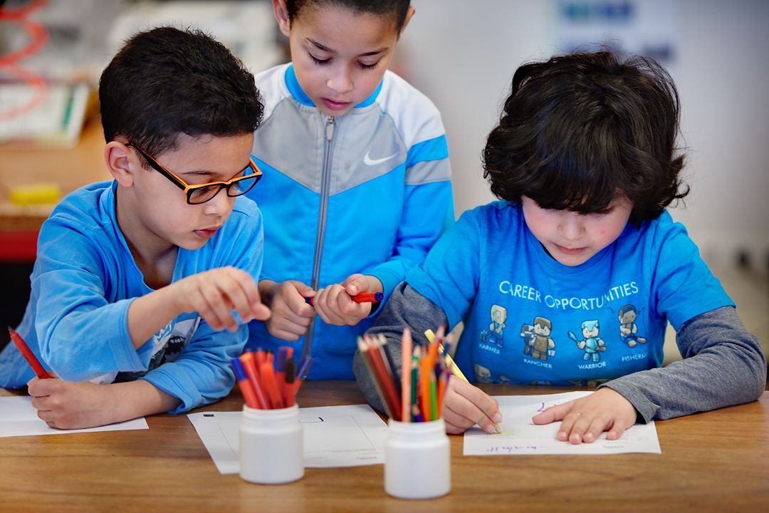 Drie kinderen zitten te tekenen.