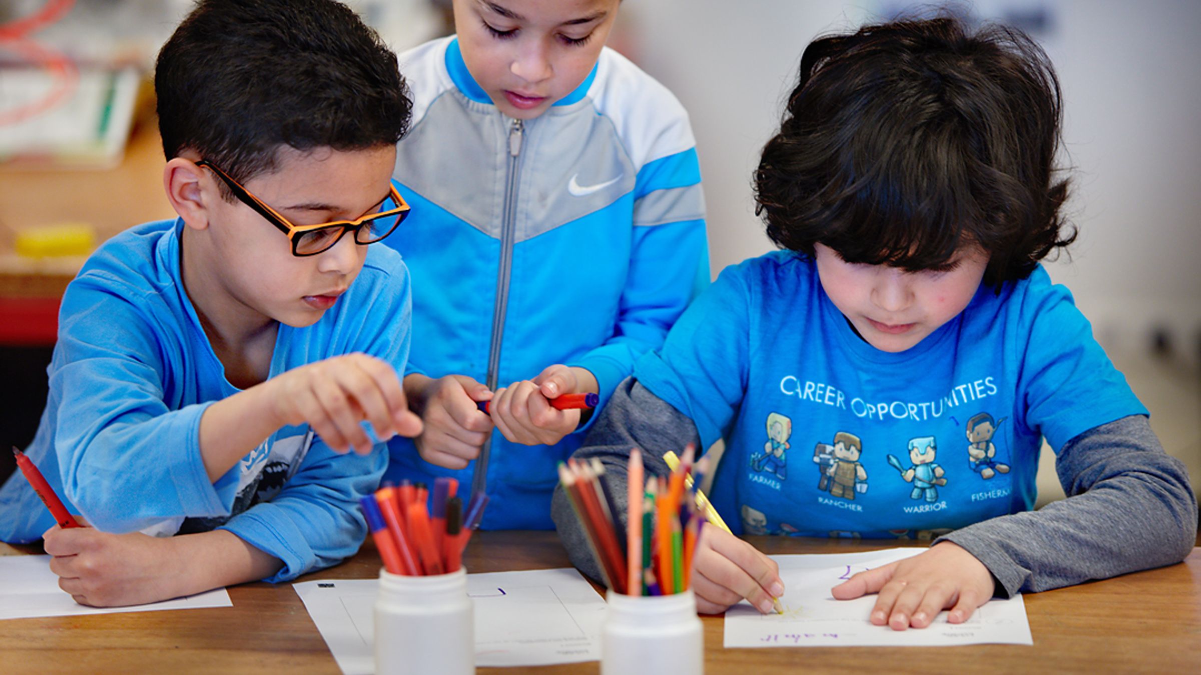 Drie kinderen zitten te tekenen.