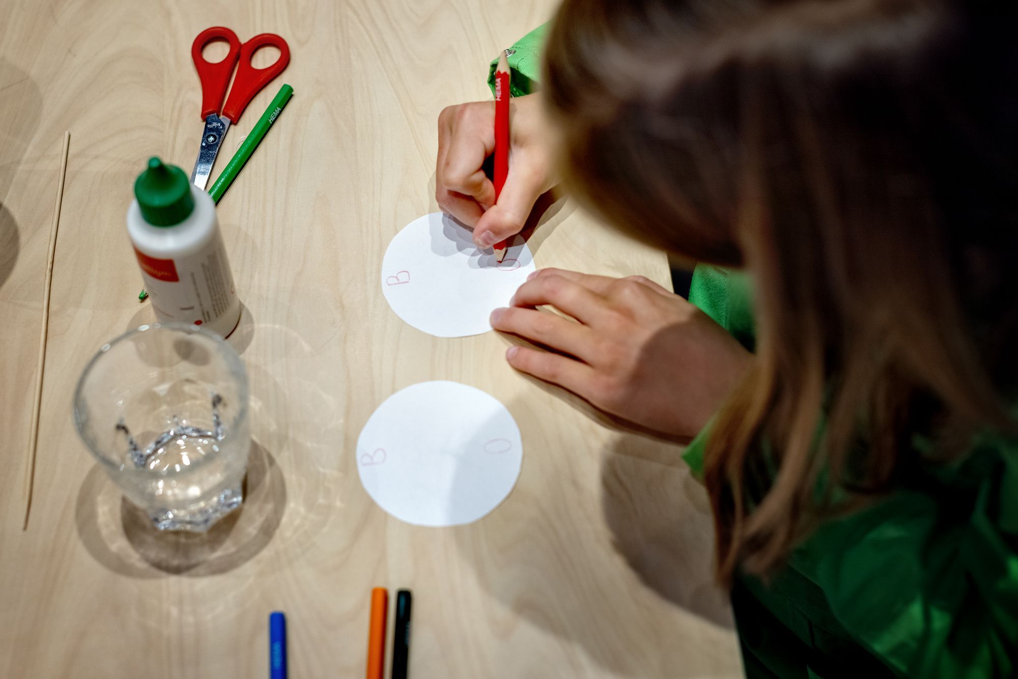 Een meisje tekent op twee rondjes papier