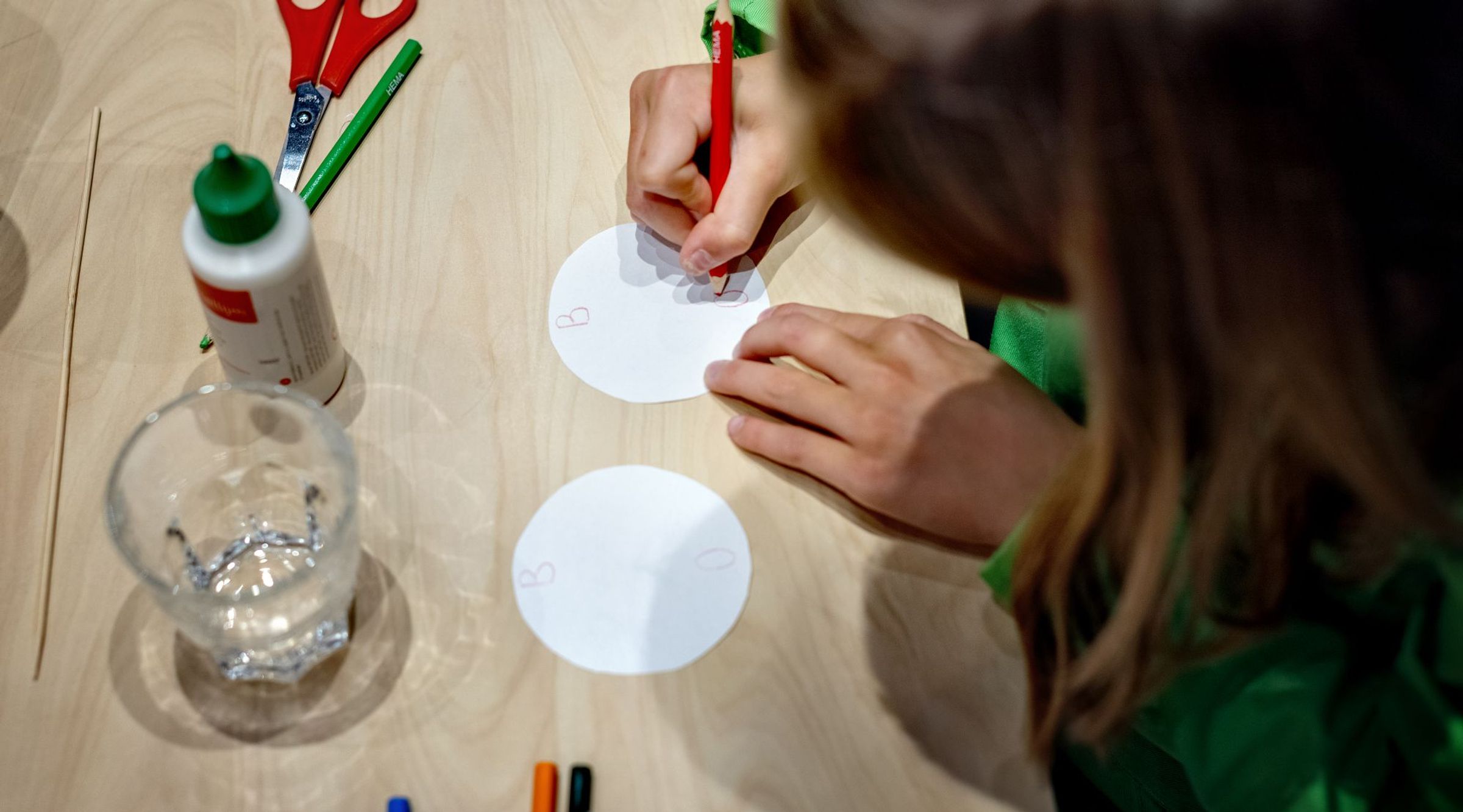 Een meisje tekent op twee rondjes papier