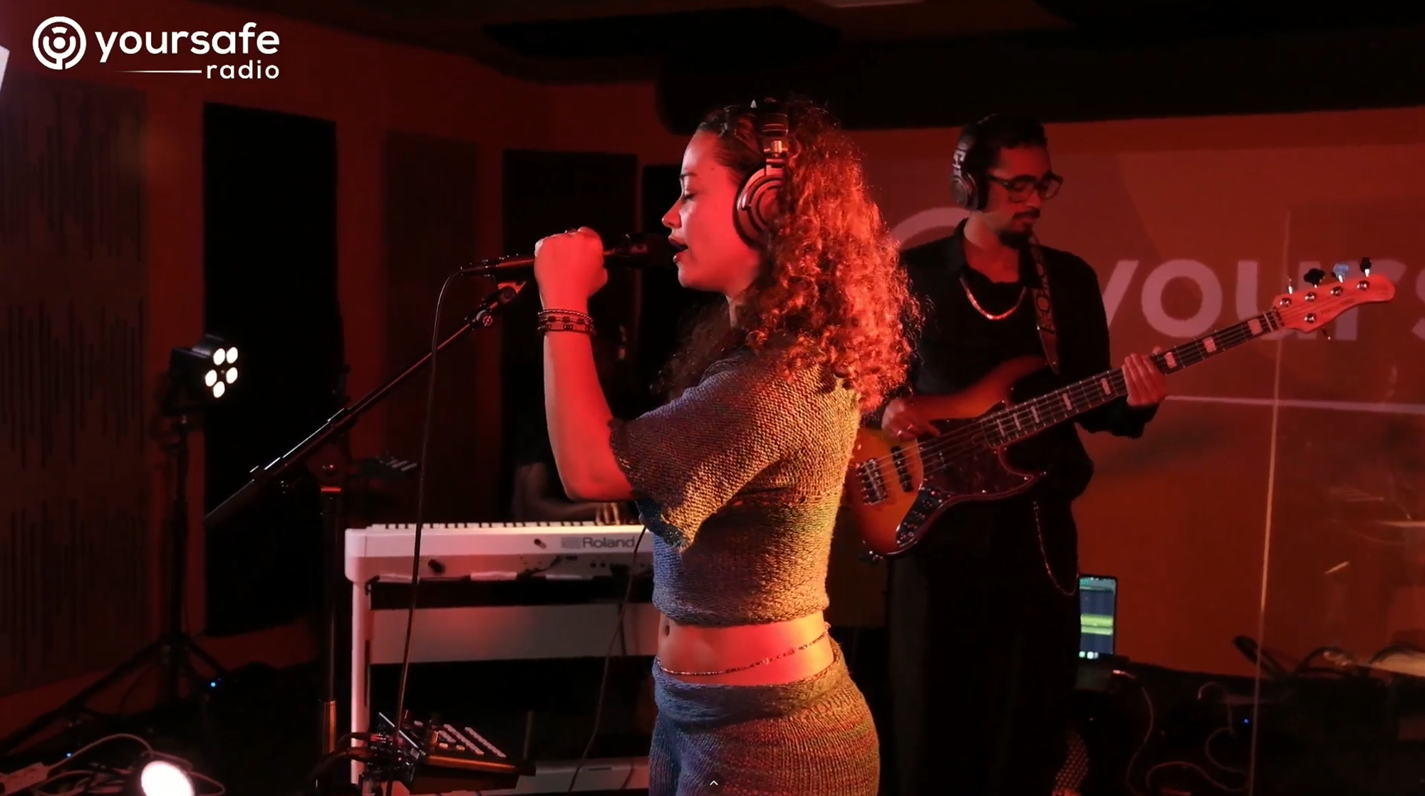 Een vrouw met krullen zingt in een microfoon met een koptelefoon op.