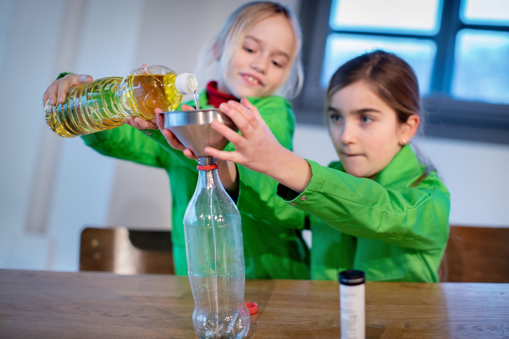 Een meisje giet olie over in een andere fles