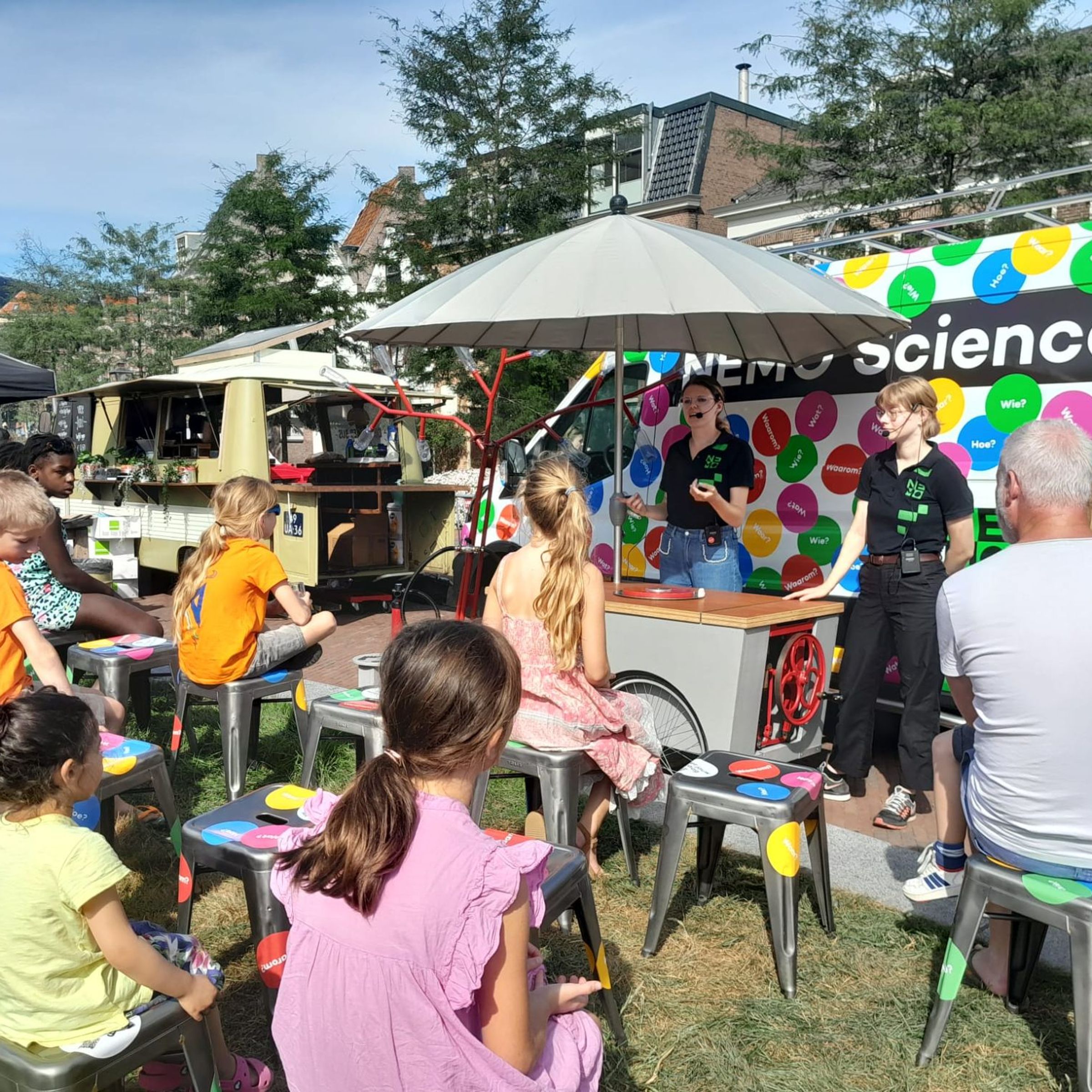 kinderen kijken naar proefjes in de open lucht bij de bus van NEMO