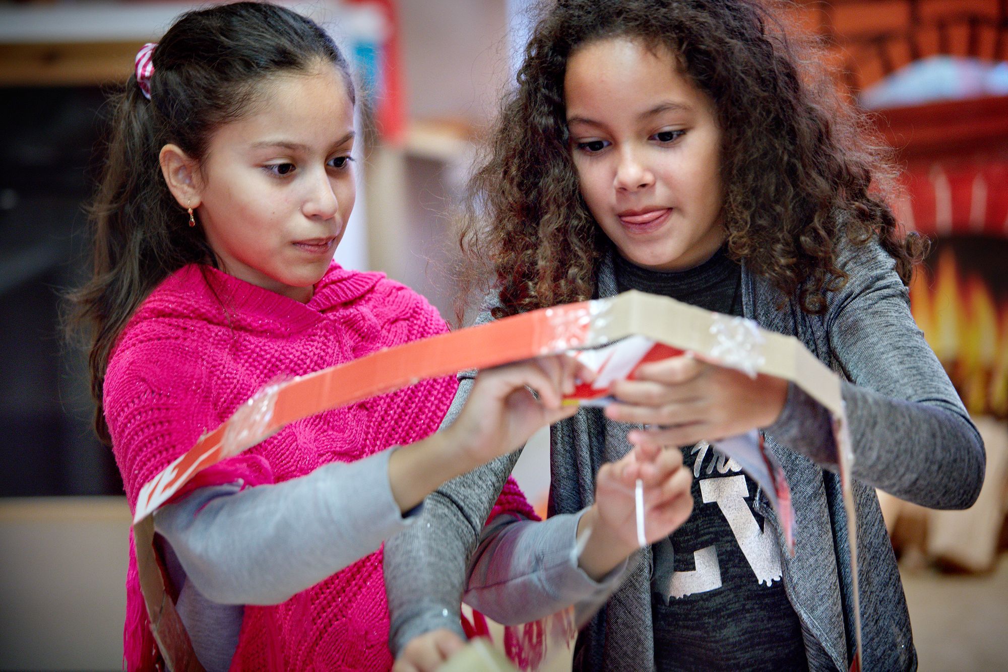 Twee kinderen werken aan een kartonnen bouwwerk.