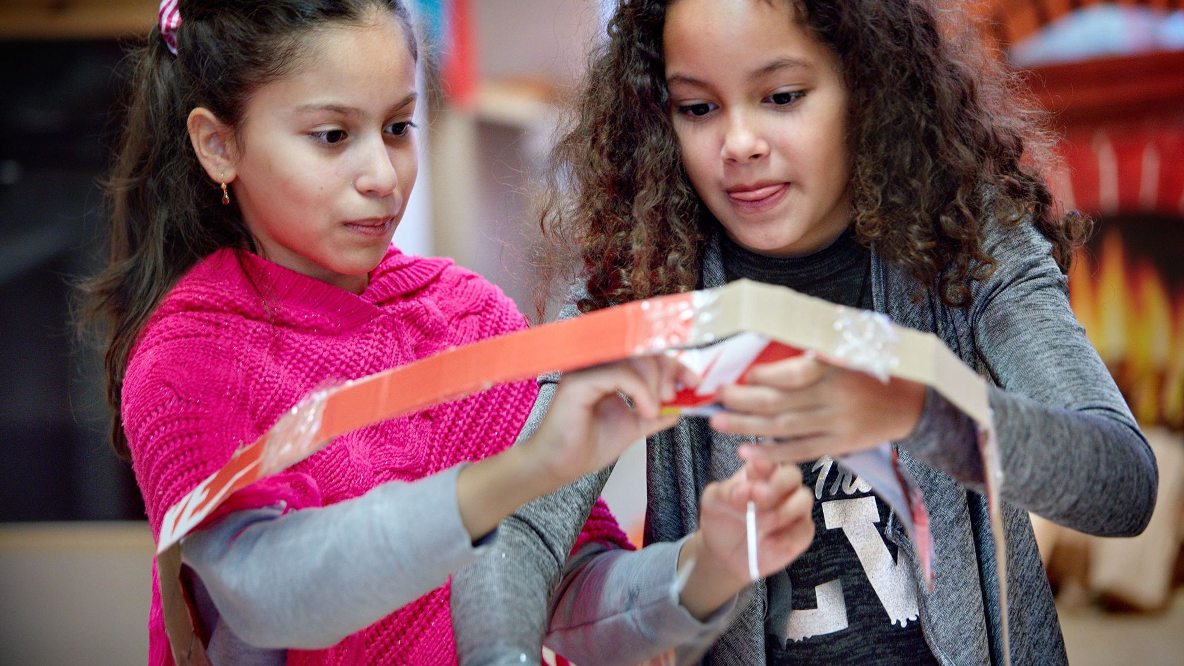 Twee kinderen werken aan een kartonnen bouwwerk.