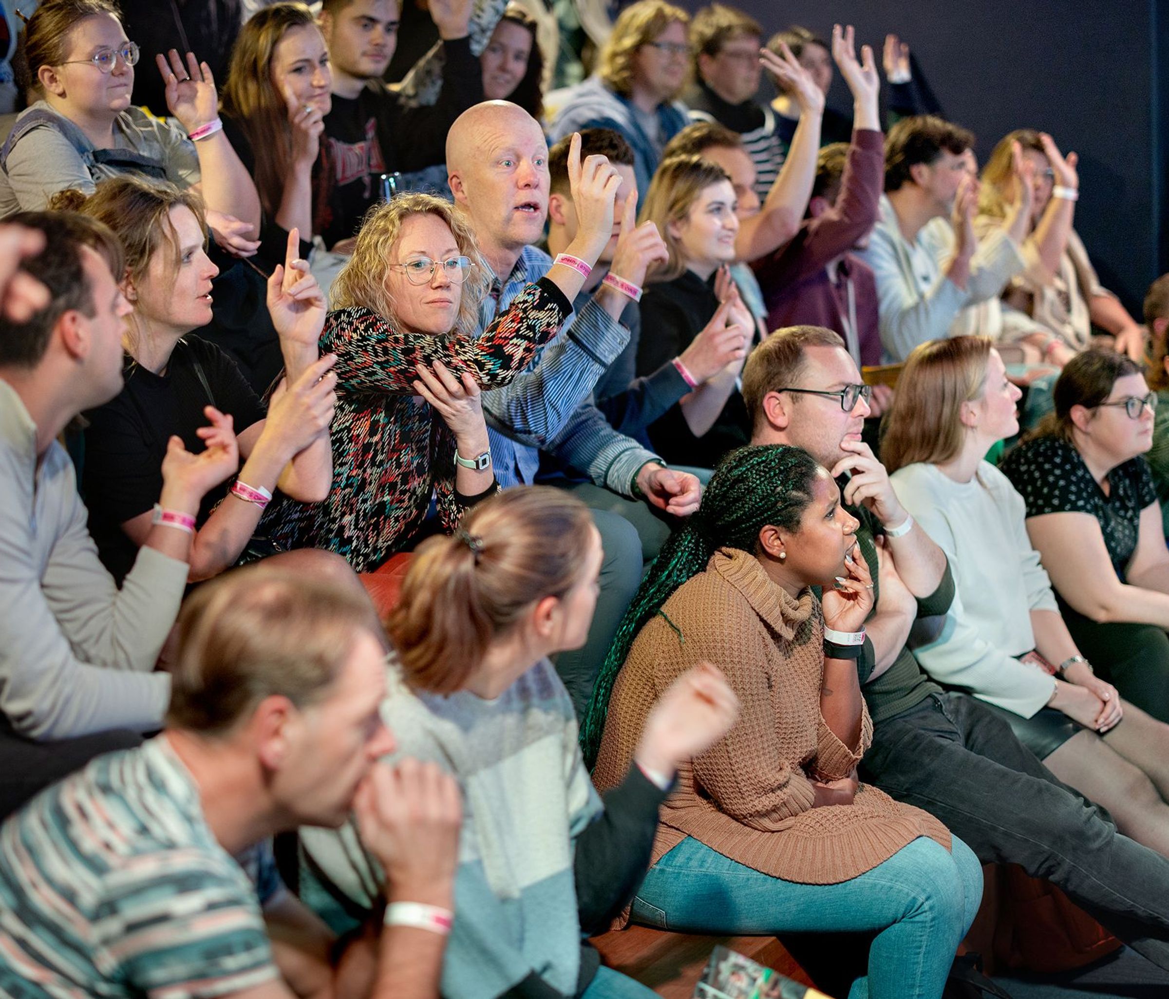 Luisterend publiek met vingers omhoog