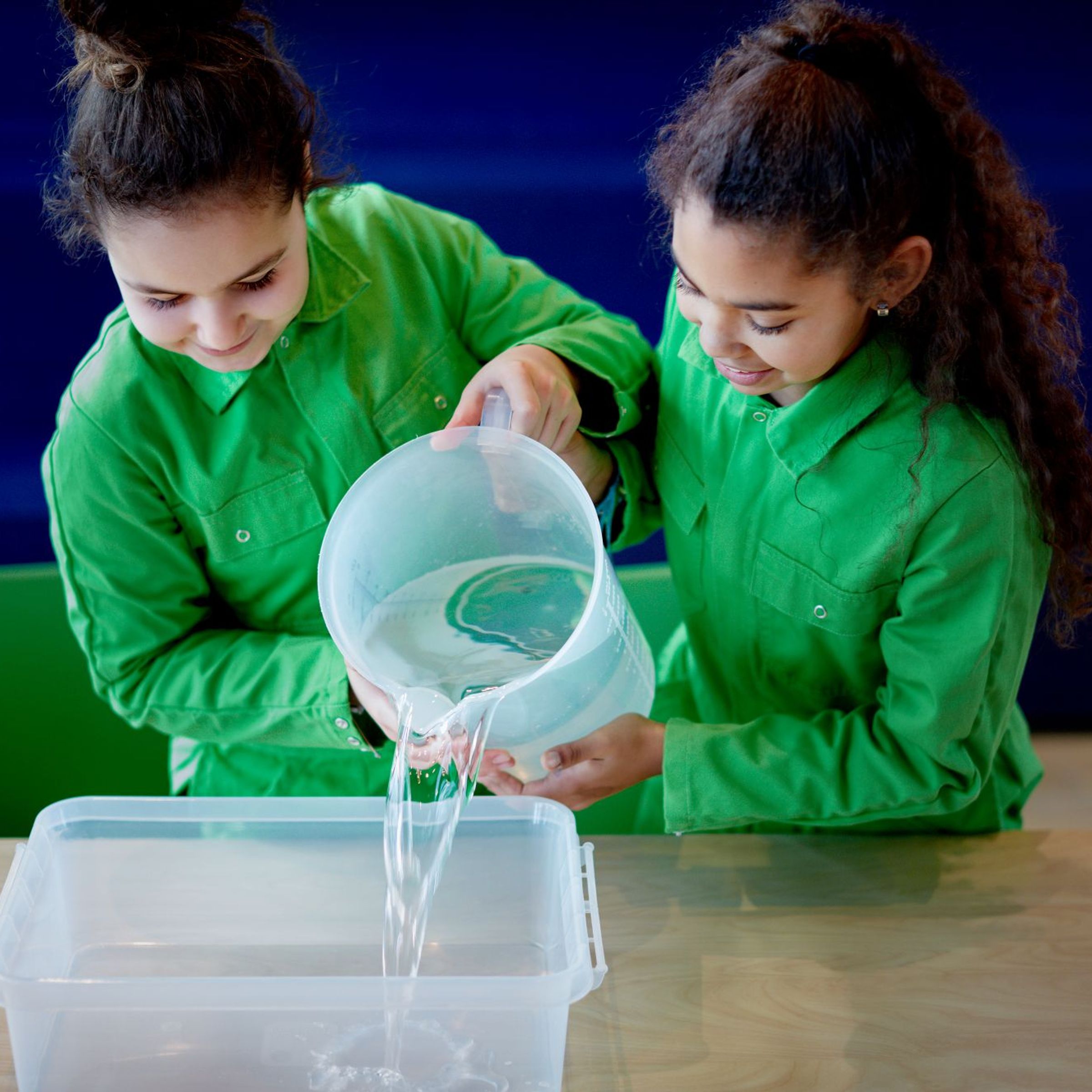 2 meisjes schenken water in een grote bak