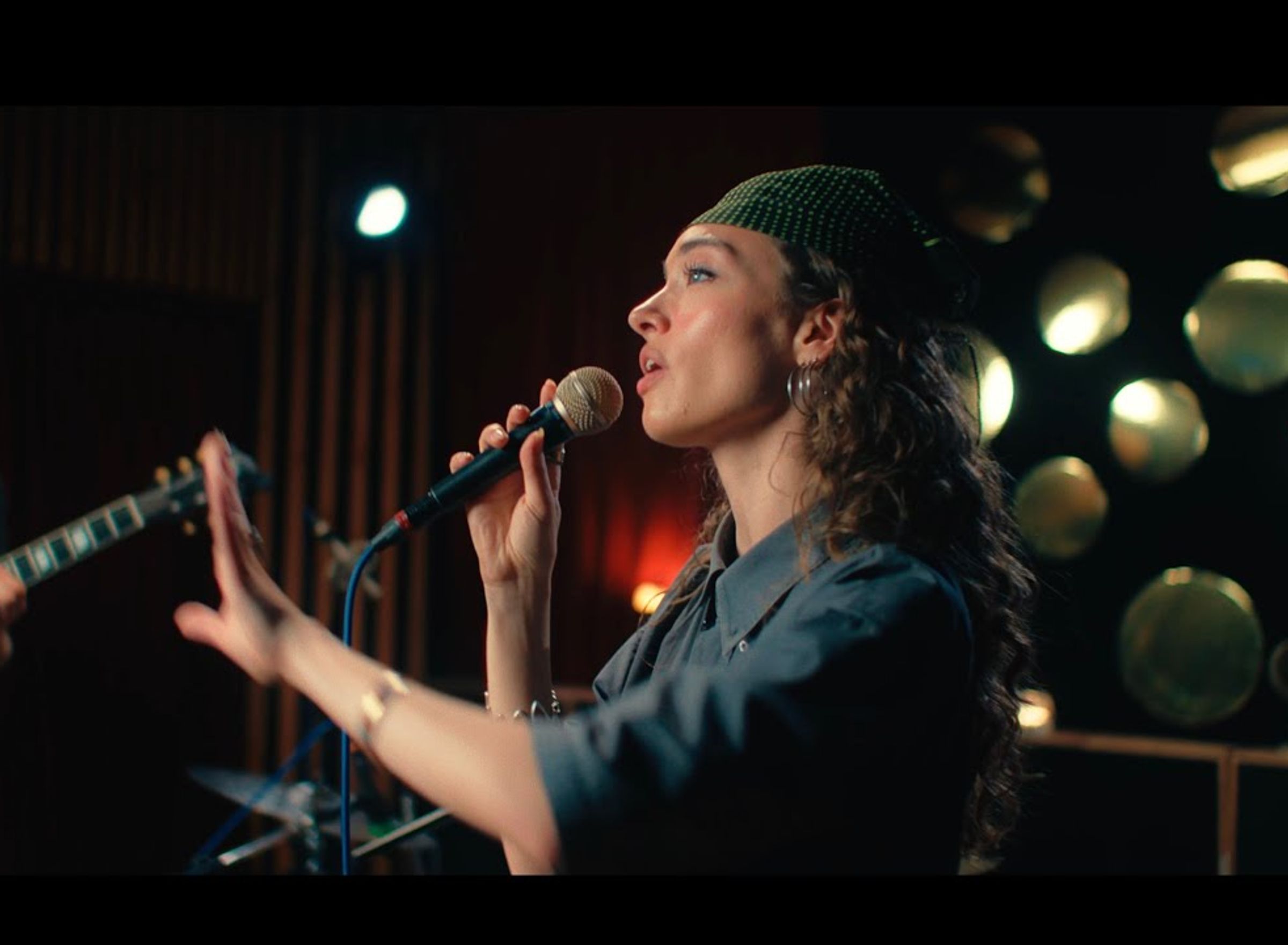 a girl with a bandana singing into a microfone