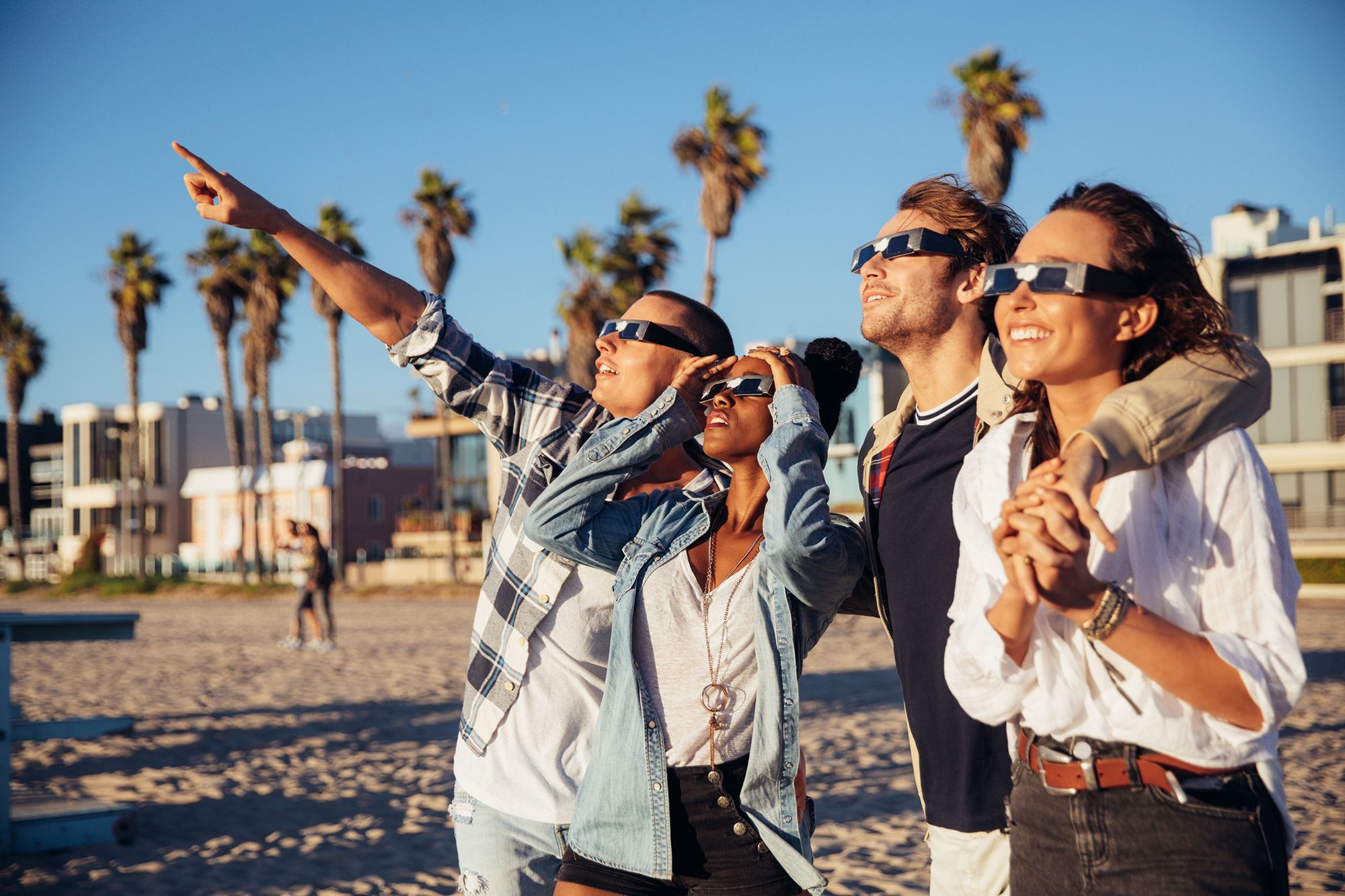 Vrienden kijken naar een solar eclips vanaf het strand