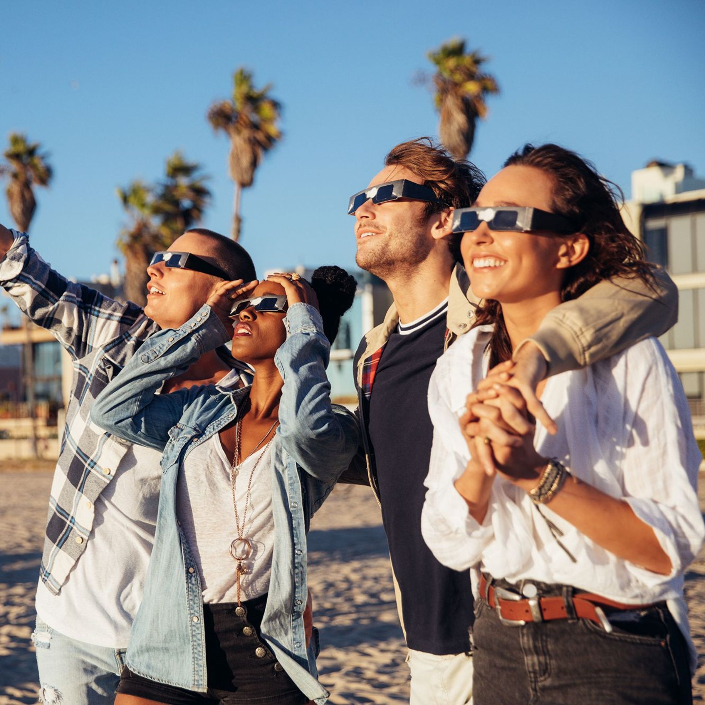 Vrienden kijken naar een solar eclips vanaf het strand